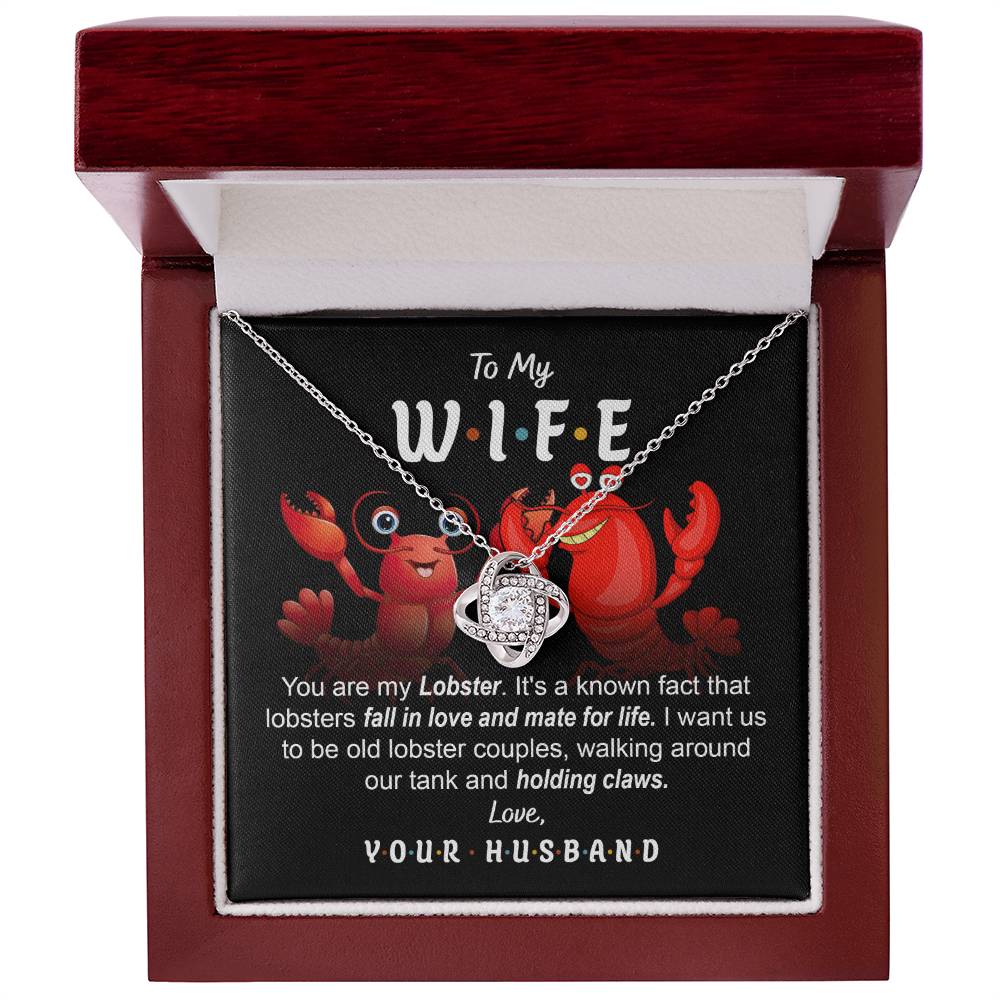 To Wife, Old Lobster Couples - Love Knot Necklace with a heart pendant displayed on a card featuring two cartoon lobsters and a message to a wife, discussing lifelong lobster mates and expressing love from a husband. The necklace sparkles with cubic zirconia crystals, symbolizing the unbreakable bond of your love.