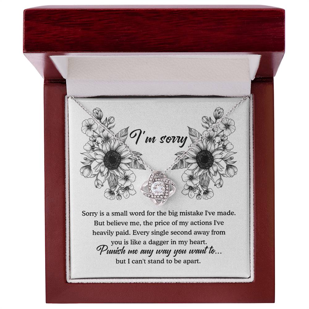 The "Sorry-Small Word - Love Knot Necklace" is a jewelry gift box that comes with an apology message. Inside, it contains a beautiful Love Knot Necklace featuring a silver pendant designed to resemble intertwined hearts, adorned with cubic zirconia crystals. The heartfelt message expresses deep regret and asks for forgiveness.