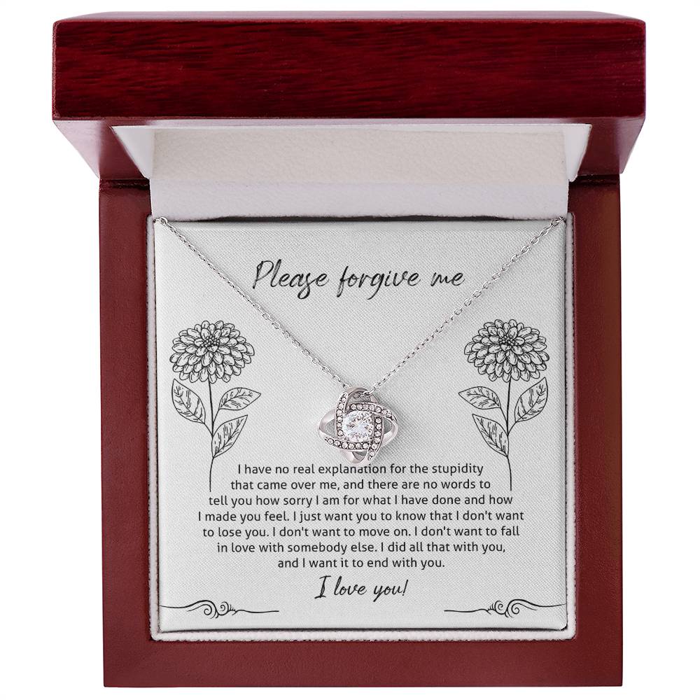 The Sorry-Real Explanation - Love Knot Necklace features an intertwined heart pendant adorned with cubic zirconia crystals, presented in a box. The box lid includes an apology note with floral illustrations, expressing regret, love, and a plea for forgiveness.