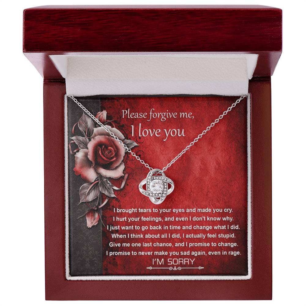 The "Sorry-One Last Chance - Love Knot Necklace" showcases an interlocking design and is elegantly displayed on a card featuring an apology message and images of red roses. Decorated with shimmering cubic zirconia crystals, this personalized gift is set against a red background with black floral accents.