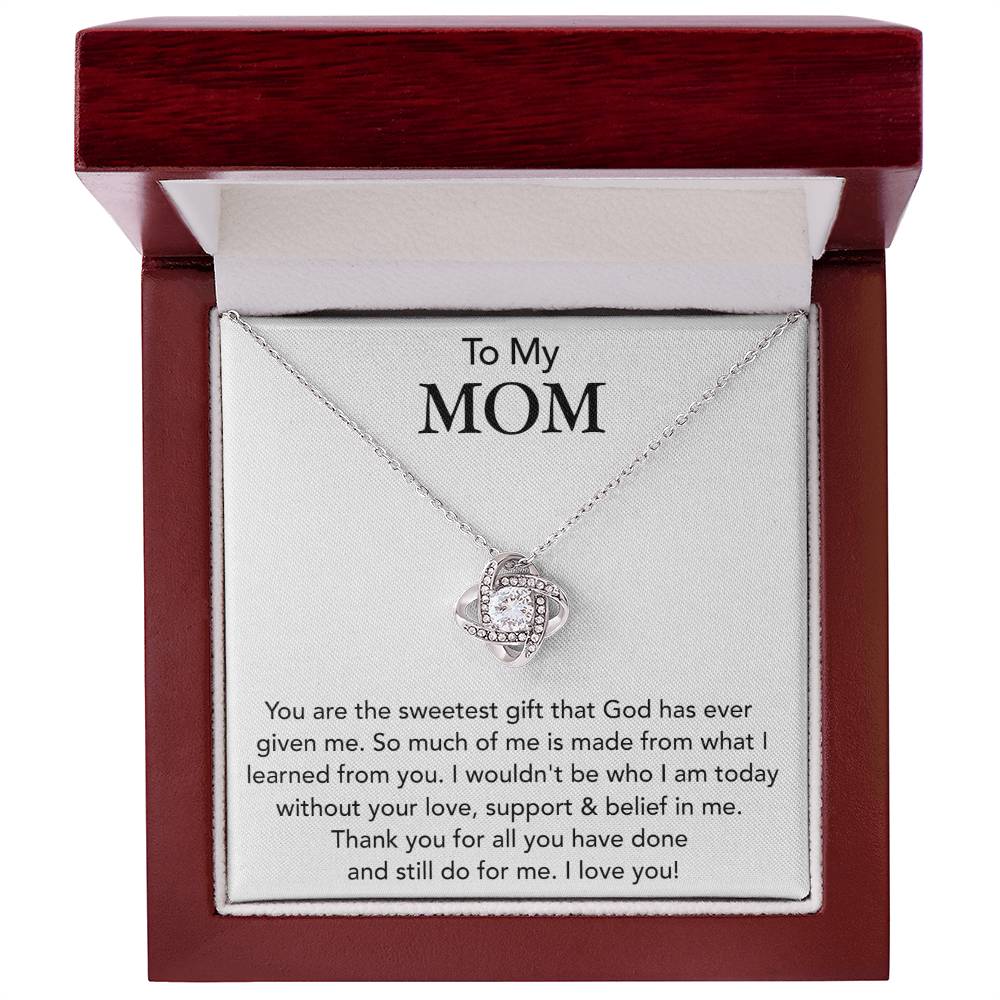 A To My Mom, You Are The Sweetest Gift That God Has Ever Given Me - Love Knot Necklace is presented in an open gift box with a heartfelt message to a mother, expressing gratitude and love. This exquisite piece is crafted in gold over stainless steel and adorned with cubic zircon by ShineOn Fulfillment.