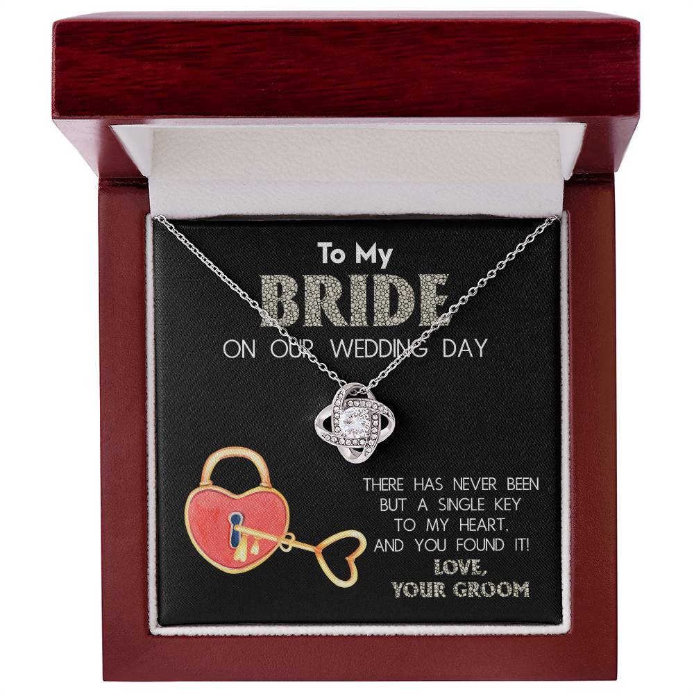 A "To My Bride, A Single Key - Love Knot Necklace" adorned with cubic zirconia crystals is displayed against a background with text that reads, "To My Bride On Our Wedding Day" and "There has never been but a single key to my heart, and you found it! Love, Your Groom.