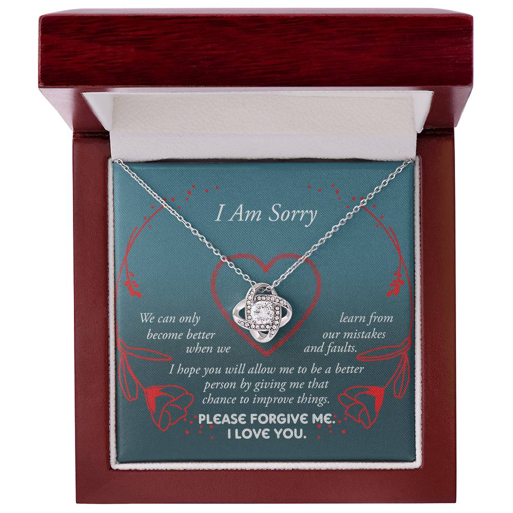 The Sorry-Mistakes And Faults - Love Knot Necklace, featuring a heart-shaped pendant with sparkling cubic zirconia set in white gold, is elegantly presented in a box adorned with the words "I Am Sorry" and a heartfelt apology message.