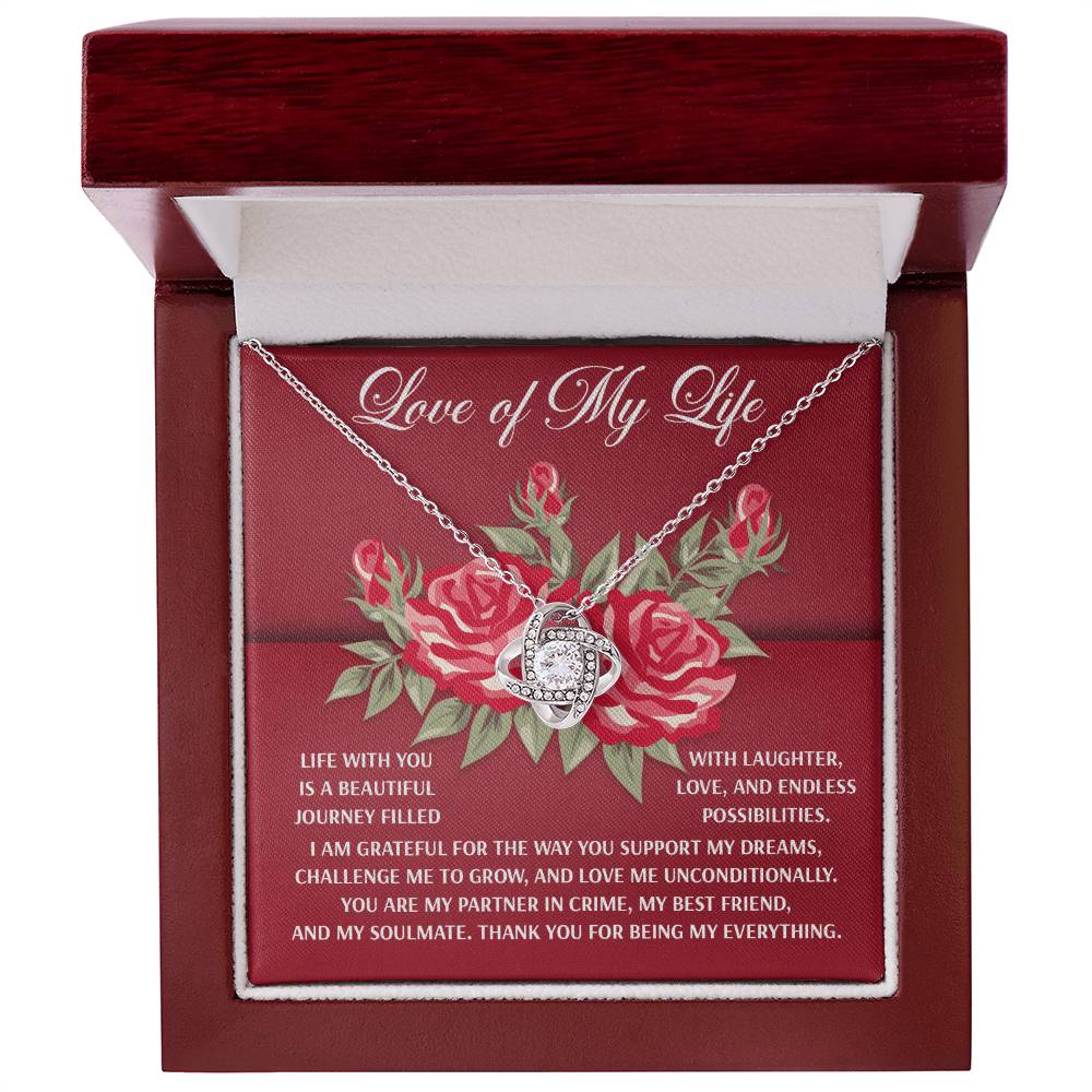 The Soulmate-Endless Possibilities - Love Knot Necklace is elegantly presented in a red box with a silver heart and crystal design, accompanied by a card with red roses and a romantic message. It features white gold plating and sparkling cubic zirconia.