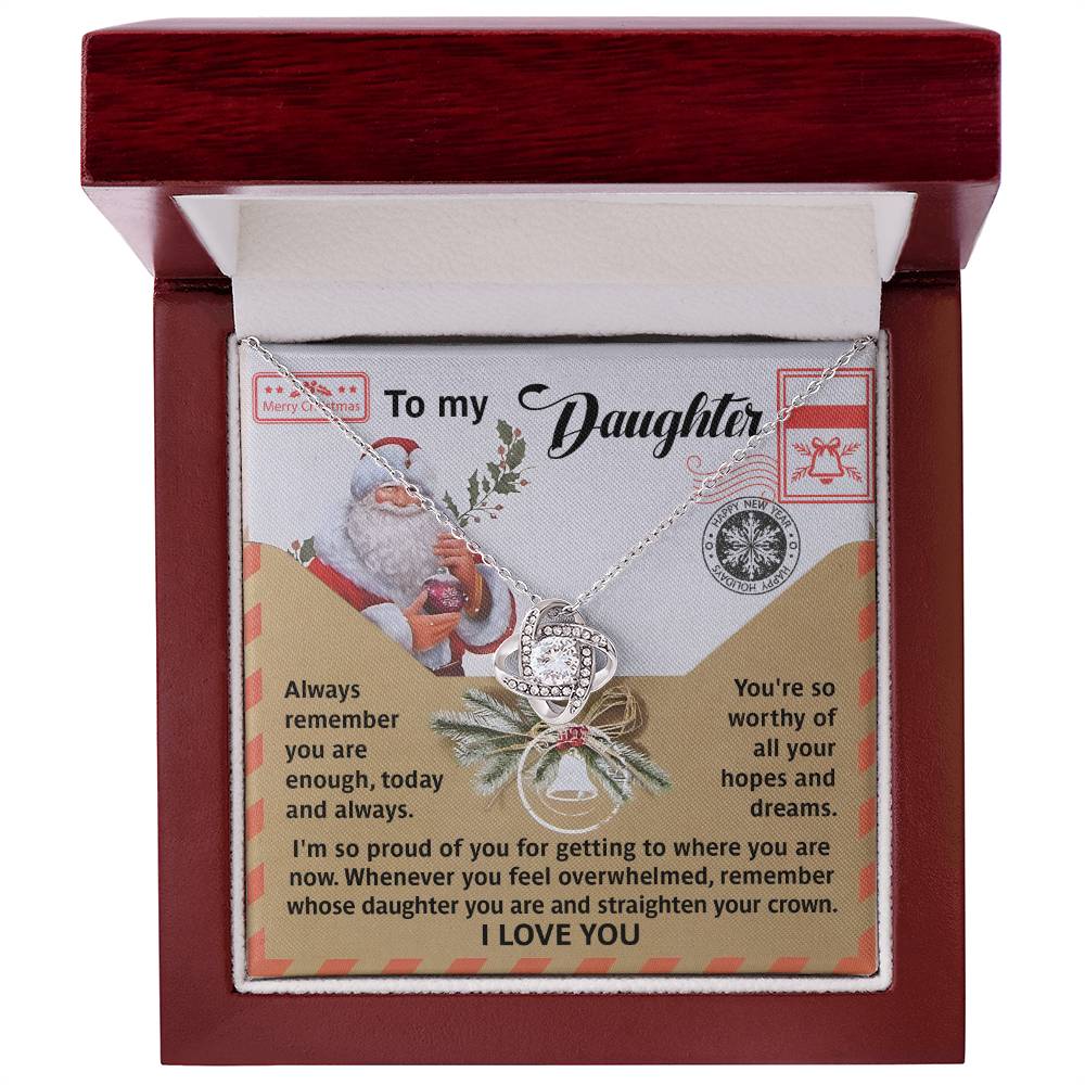 The Daughter-All Your Hopes - Love Knot Necklace, featuring a heart-shaped pendant and sparkling with cubic zirconia crystals, is beautifully displayed in an open box. Accompanying it is a card titled "To my Daughter," which presents a heartfelt message alongside an illustration of Santa Claus.