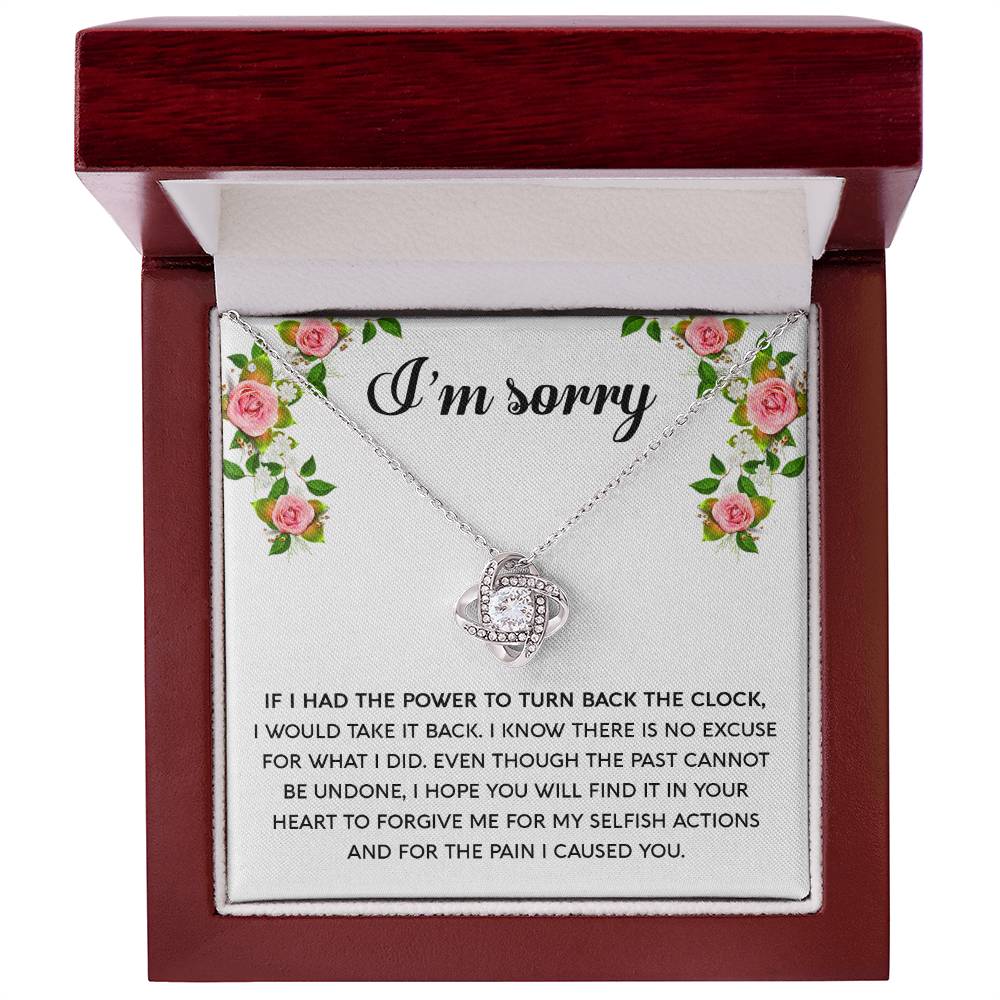 The "Sorry, Make It Right - Love Knot Necklace," featuring a silver intertwined knot pendant adorned with cubic zirconia crystals, is beautifully displayed in a box. The text on the box reads, "I’m sorry," with an apology message below, framed by a floral border in the top corners.