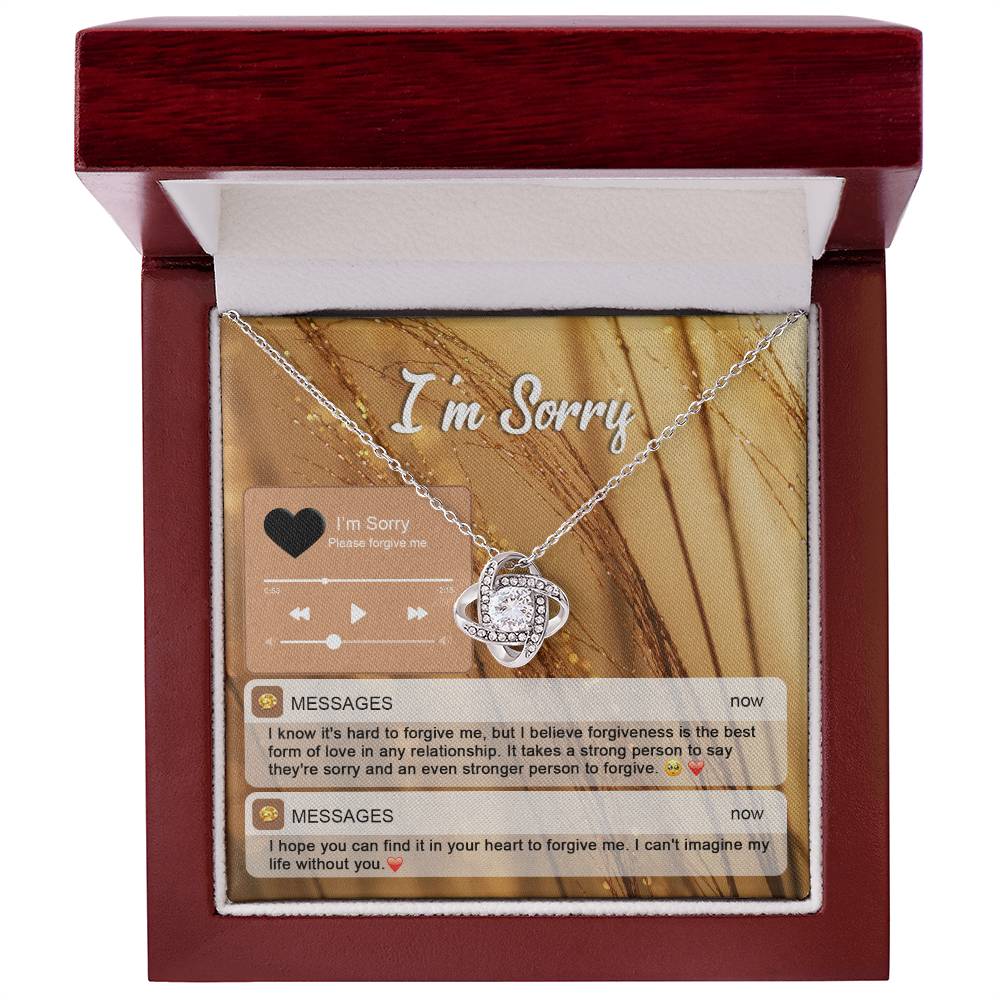 The "Sorry, Person To Forgive - Love Knot Necklace" features a gold finish and sparkling cubic zirconia crystals. It is presented on a card adorned with musical notes and icons that reads "I'm Sorry," along with heartfelt messages of apology and pleas for forgiveness.