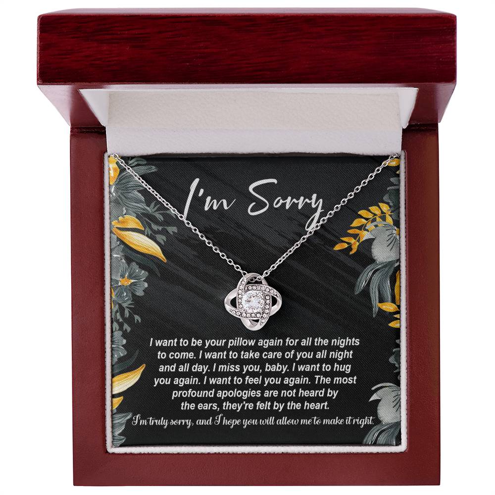 The "Sorry, Be Your Pillow - Love Knot Necklace" features an intertwined heart pendant adorned with cubic zirconia crystals. It comes in a gift box inscribed with "I'm Sorry" and includes a heartfelt apology message expressing regret and a desire for reconciliation.