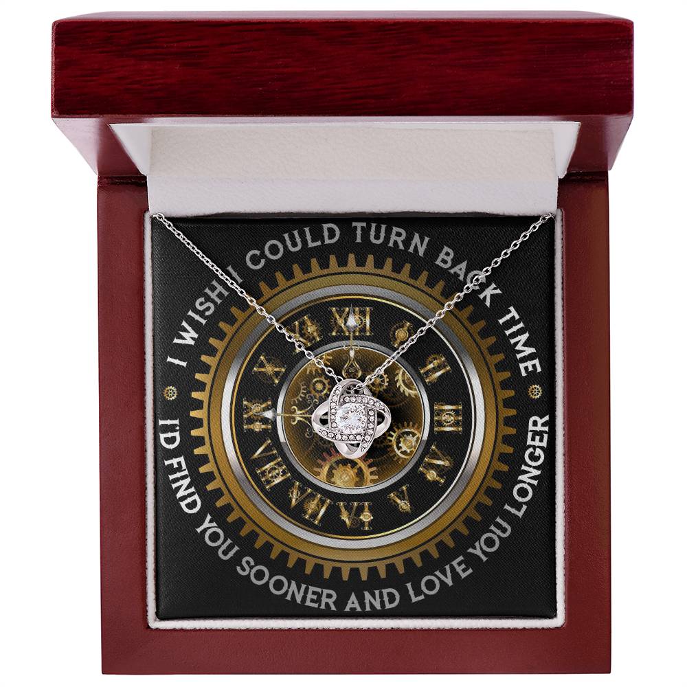 The "To Wife, Turn Back Time - Love Knot Necklace," adorned with cubic zirconia crystals, is elegantly displayed against a clock design backdrop. The text around the clock reads, "I WISH I COULD TURN BACK TIME, I'D FIND YOU SOONER AND LOVE YOU LONGER.