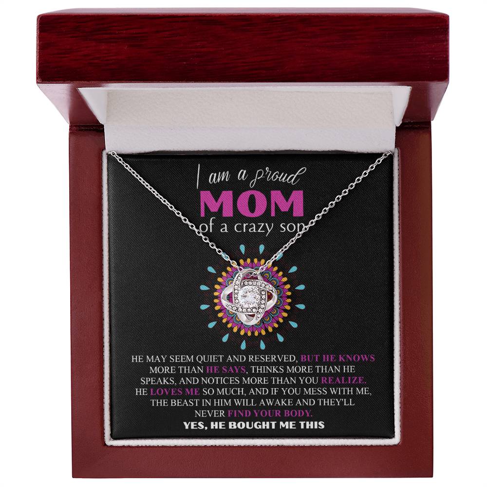 The To Mom, Proud Mom - Love Knot Necklace features a heart-shaped pendant crafted from 14k white gold, adorned with cubic zirconia crystals, and rests inside a red box. The enclosed message reads, "I am a proud mom of a crazy son," highlighting his protective nature.