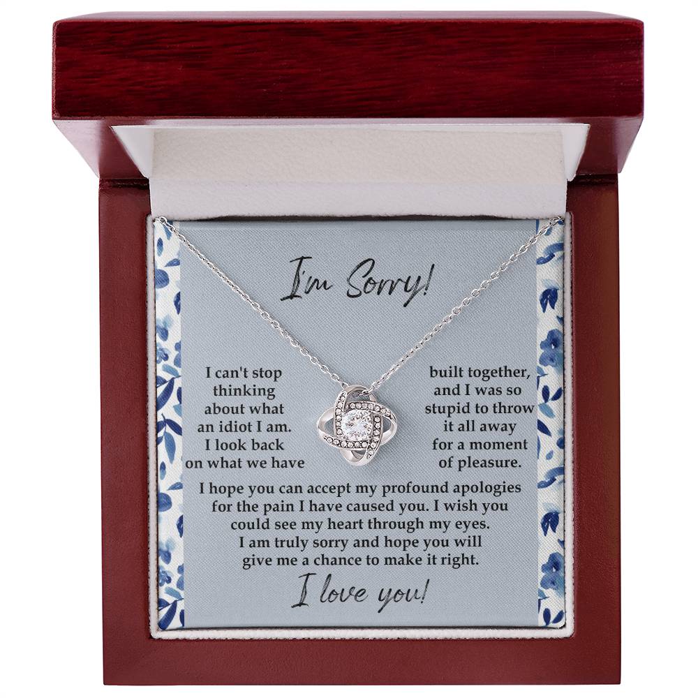 The "Sorry-Through My Eyes - Love Knot Necklace," adorned with cubic zirconia crystals and a white gold finish, is presented on a card featuring a heartfelt apology message, expressing regret for causing pain and seeking forgiveness.