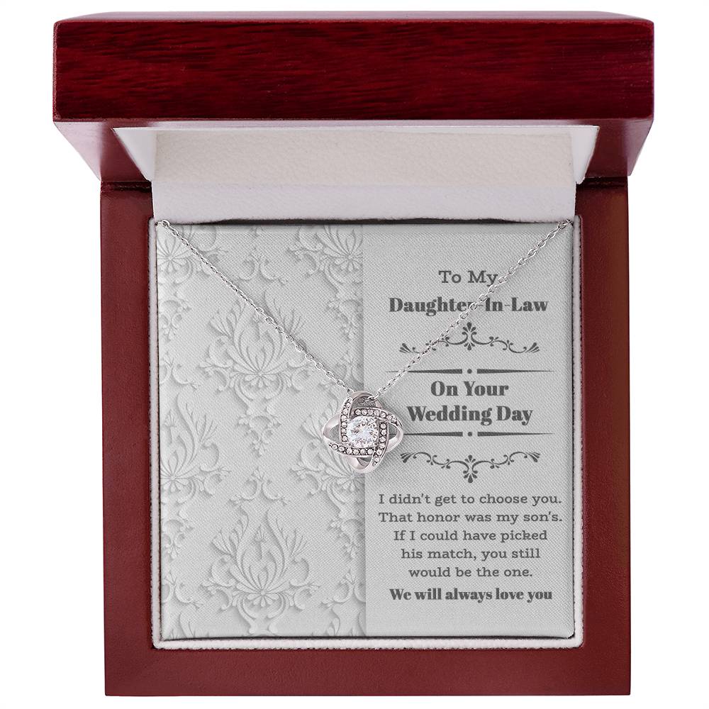 To My Daughter-In-Law Wedding, Be The One - Love Knot Necklace with an intertwined heart design, adorned with cubic zirconia crystals, displayed on a decorative backing card. The card reads: "To My Daughter-In-Law On Your Wedding Day" with a sentimental message below. Perfect as a gift for a loved one.