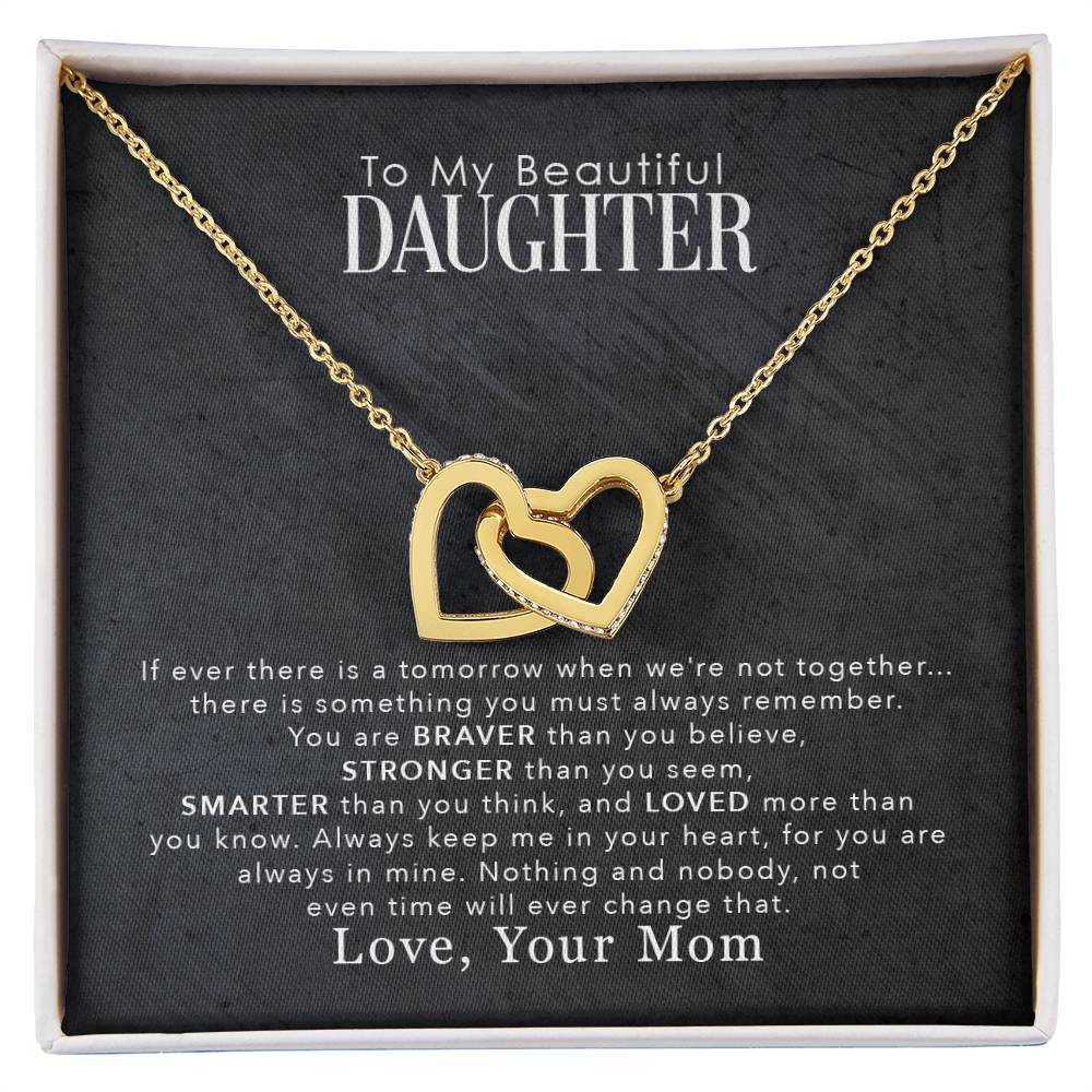 A gift box containing a To My Beautiful Daughter, You Are Braver Than You Believe - Interlocking Hearts Necklace with cubic zirconia crystals and an inspirational message addressed to a daughter from a mother.