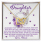 The Daughter-Angel Heart necklace features interlocking hearts adorned with sparkling cubic zirconia crystals, presented in a box saying, "To My Beautiful Daughter," surrounded by purple roses and butterflies, underscoring a mother's love and commitment.