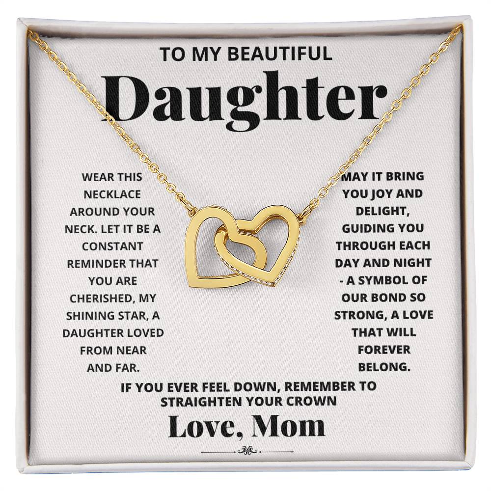 A "To My Daughter, Wear This Necklace - Interlocking Hearts Necklace" with interlocking heart pendants adorned with cubic zirconia crystals on a printed message card from a mother to her daughter, expressing love and encouragement.