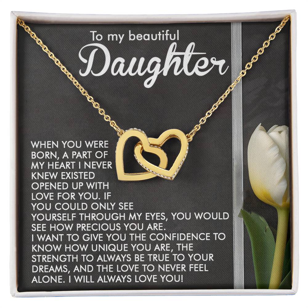 The Daughter-Heart Love necklace, with a rose gold interlocking hearts design and sparkling cubic zirconia crystals, is displayed on a card featuring a heartfelt message to a daughter. It sits elegantly beside a white tulip, symbolizing love and elegance.