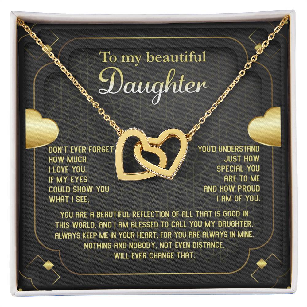 The "To Daughter, Beautiful Reflection - Interlocking Hearts Necklace" features an 18k yellow gold finish and is presented on a card that conveys a heartfelt message of love, pride, and eternal connection. The interlocking hearts are adorned with sparkling cubic zirconia crystals.