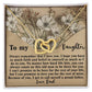 The Daughter-Proud Father Interlocking Hearts Necklace with a rose gold finish glistens against a floral background, accompanied by a heartfelt message from a father to his daughter expressing love, faith, and pride.