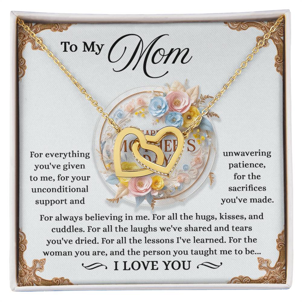 The Mom-Taught Me Interlocking Hearts Necklace features cubic zirconia crystals and a heartfelt message to "Mom," expressing gratitude for her love, patience, and sacrifices. The decorative backdrop enhances its beauty, concluding with a touching "I love you.