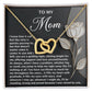 The Mom-Guiding Light Interlocking Hearts Necklace in gold, adorned with cubic zirconia crystals, features a rose-accented card with a heartfelt message of gratitude and love for a mother's support and sacrifices. It's the perfect gift for her.