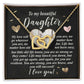 The "Daughter-Your Strength" Interlocking Hearts Necklace features a beautiful rose gold finish with a gold heart design. It comes in a box with an inspiring message for daughters and is set against a shimmering background adorned with small gold heart accents.