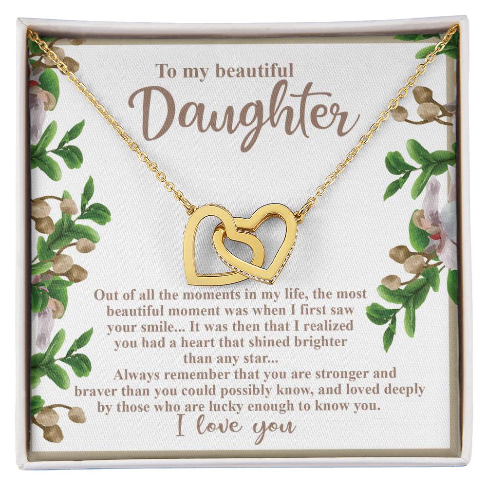 The Daughter-First Smile - Interlocking Hearts Necklace, embellished with cubic zirconia crystals, is presented on a floral card that reads: "To my beautiful Daughter," expressing love and admiration while encouraging strength and bravery.