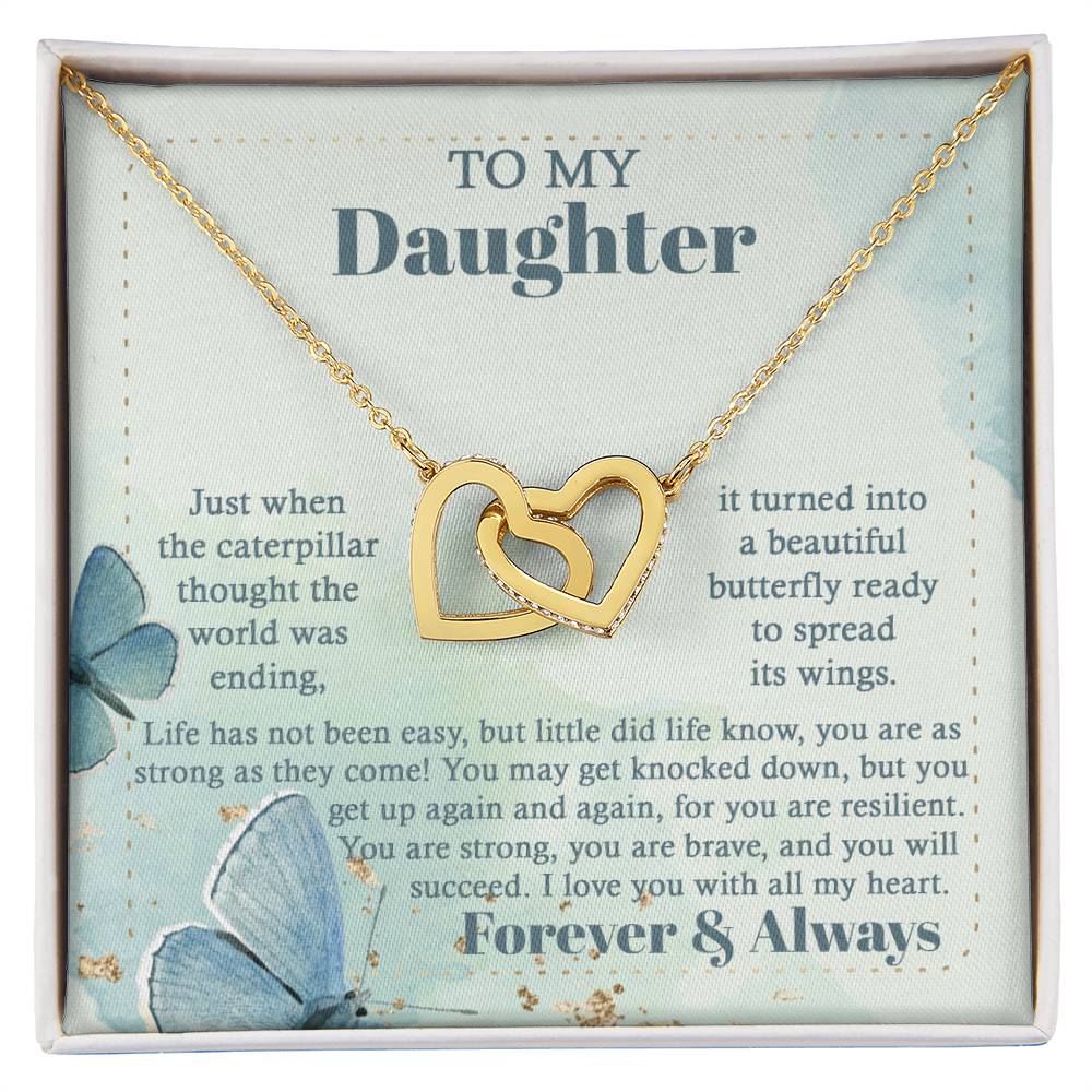 The "To Daughter, Beautiful Butterfly - Interlocking Hearts Necklace" is beautifully presented in a box adorned with blue butterflies and motivational messages about resilience and love. Sparkling with cubic zirconia crystals, this adjustable-length necklace ensures a perfect fit, making it a treasured keepsake for your daughter.