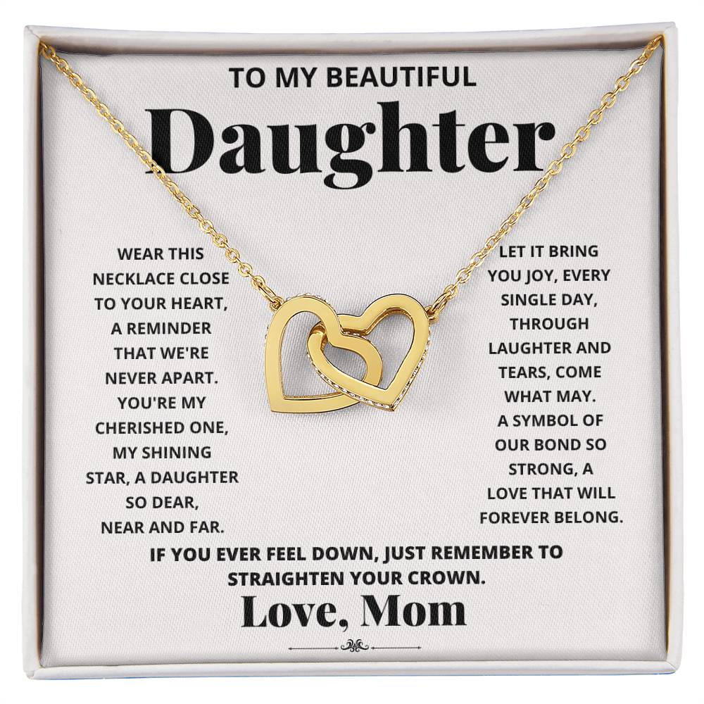 A "To My Beautiful Daughter, Wear This Necklace - Interlocking Hearts Necklace" with interlocking hearts pendants adorned with cubic zirconia crystals, presented in a box with a heartfelt message from a mother to her daughter.