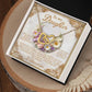 The Daughter-Heart Happiness necklace in rose gold finish features interlocking hearts with cubic zirconia crystals, elegantly presented on a decorative card with a heartfelt message for a daughter, enhanced by floral designs and ornate borders on a lace-accented wooden surface.