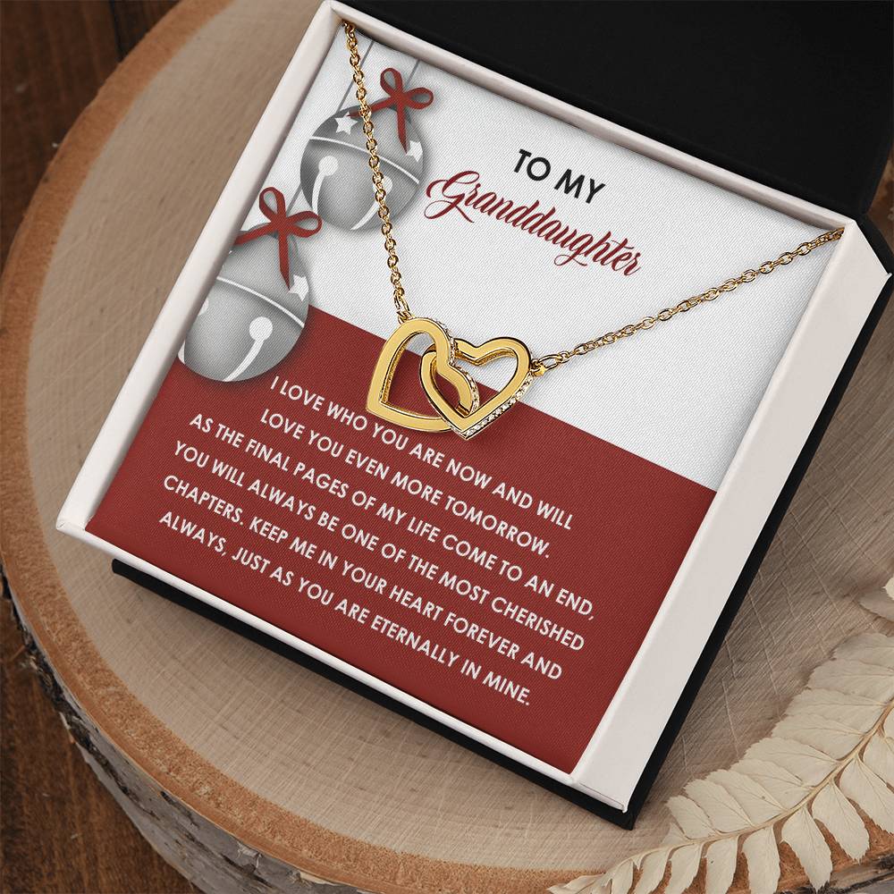 The Granddaughter-To An End - Interlocking Hearts Necklace, featuring cubic zirconia crystals, is beautifully displayed on a card within a box. The card reads "To My Granddaughter," with a touching message underneath. Its radiant rose gold finish enhances this precious gift with love and elegance.