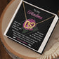 The Grandma-Love For Me - Interlocking Hearts Necklace with a rose gold finish sparkles with cubic zirconia crystals in an open gift box. The box says "To my Grandma" and includes a message of love, support, and gratitude, with a pink flower on the card behind the necklace.