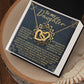 The Daughter-Reach Stars - Interlocking Hearts Necklace, featuring gold hearts and cubic zirconia crystals, sparkles in a gift box with a card titled "To my Daughter" conveying a message of happiness, belief, and care. The box sits charmingly on a wooden surface accompanied by feathers.