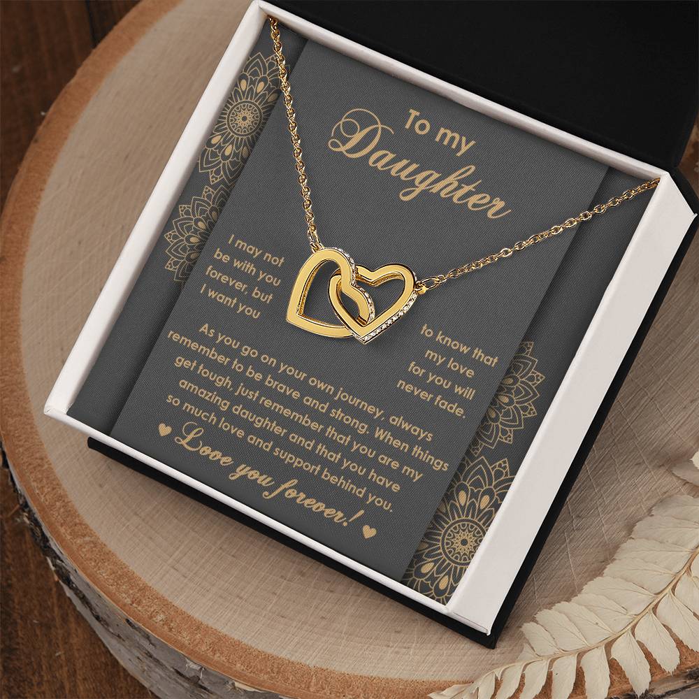 The "To Daughter, Brave And Strong 2 - Interlocking Hearts Necklace" features high-quality polished surgical steel and sparkling cubic zirconia crystals. It is presented on a card adorned with an inspiring message for your daughter, expressing love and encouragement.