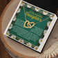 The Daughter-Your Journey - Interlocking Hearts Necklace, featuring a gold design with cubic zirconia crystals, is displayed in an open box. The background has white daisies and a heartfelt message expressing love and encouragement to a daughter.