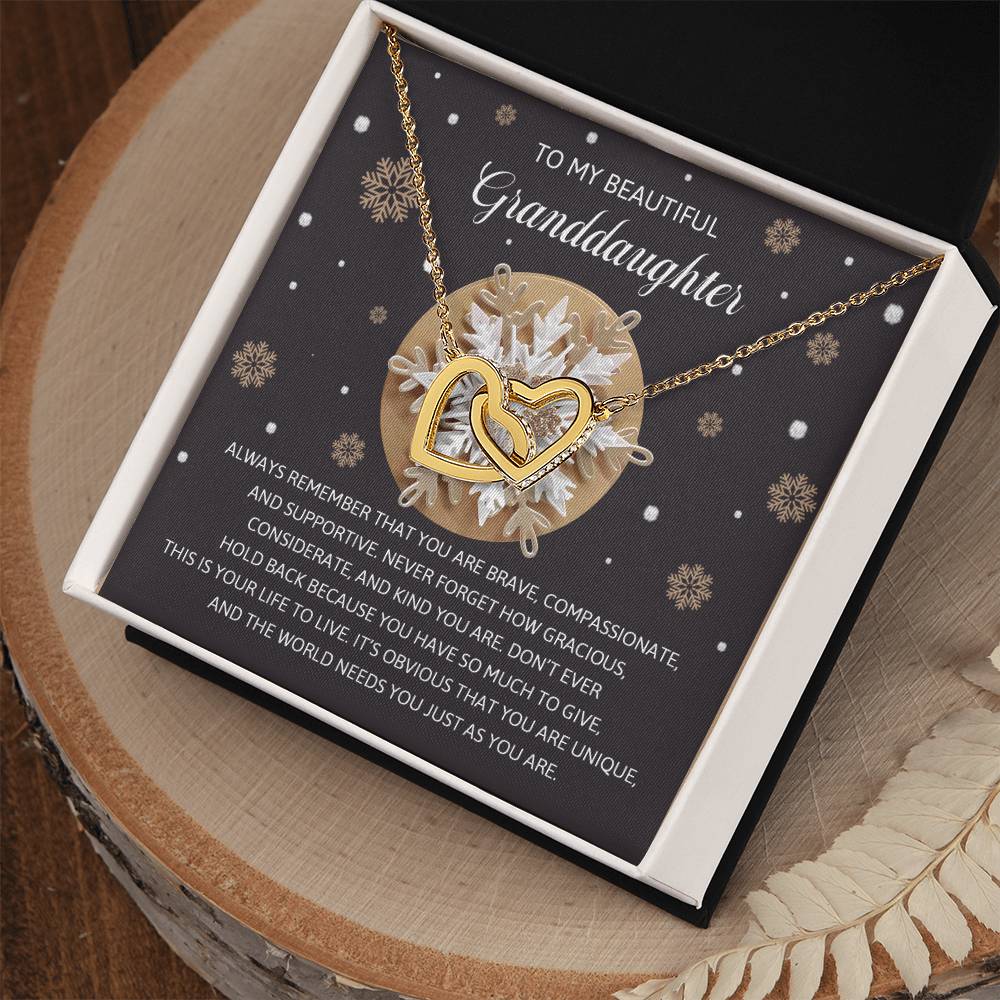 The "Granddaughter-As You Are - Interlocking Hearts Necklace" is embellished with cubic zirconia crystals and comes with a touching message for a granddaughter, elegantly presented on a decorative card featuring a snowflake and gift background.