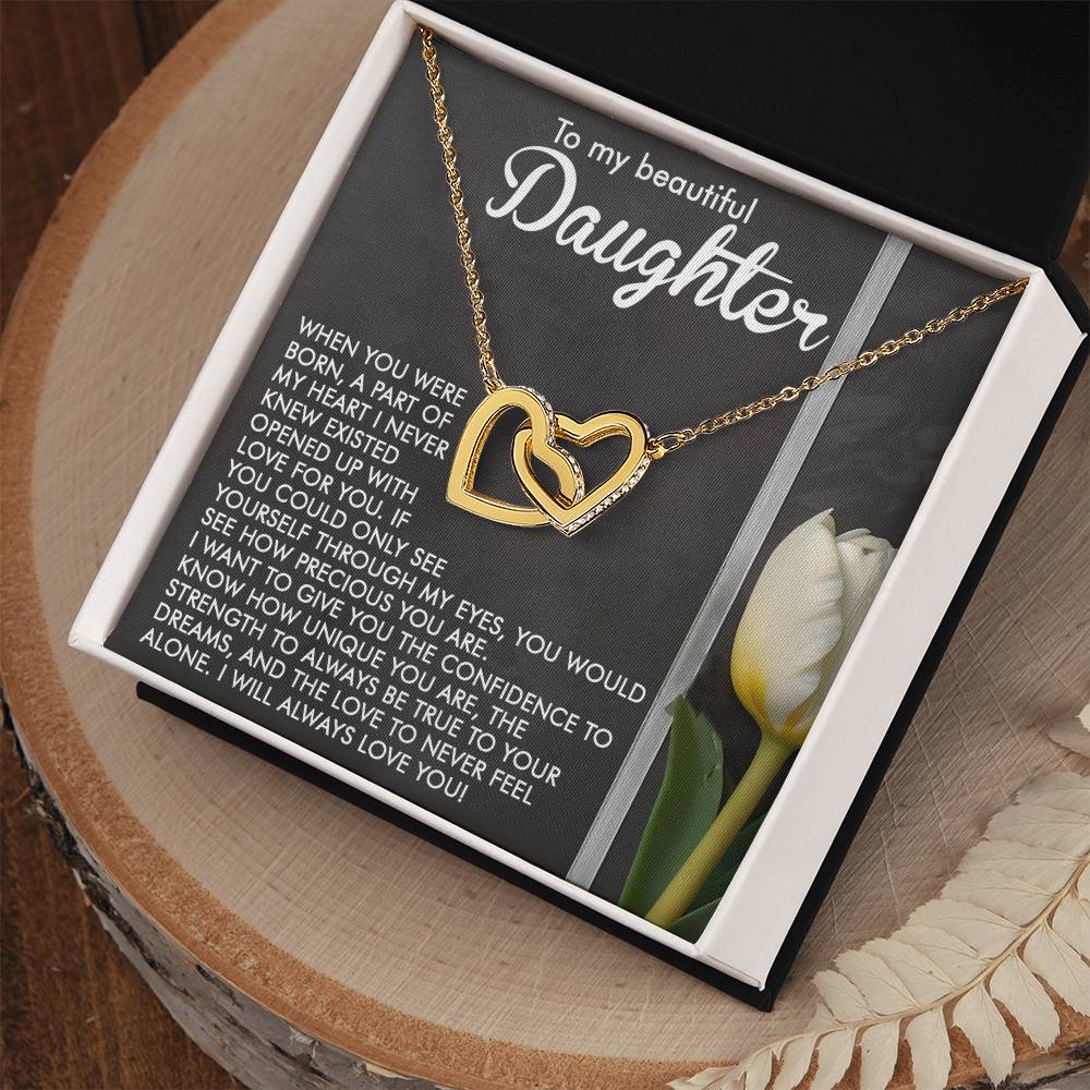 The Daughter-Heart Love - Interlocking Hearts Necklace featuring a rose gold finish is elegantly presented in a black box. An emotional message on the background expresses love, urging the daughter to see herself through her giver's eyes. A white rose adorns the scene beside the box.