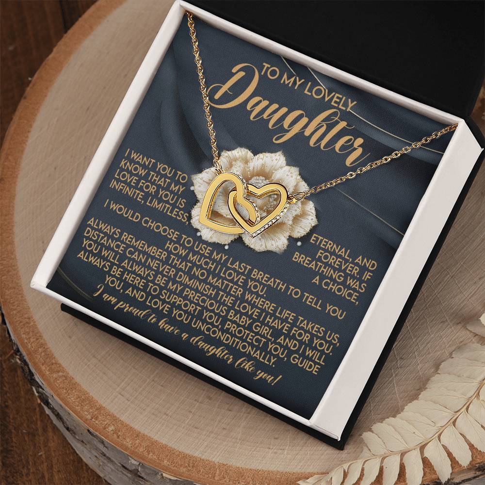 The elegant gift box of the Daughter-Infinite Love - Interlocking Hearts Necklace, adorned with cubic zirconia crystals, bears a lid that reads "To My Lovely Daughter" and a message of eternal love, all resting gracefully on a wooden surface.
