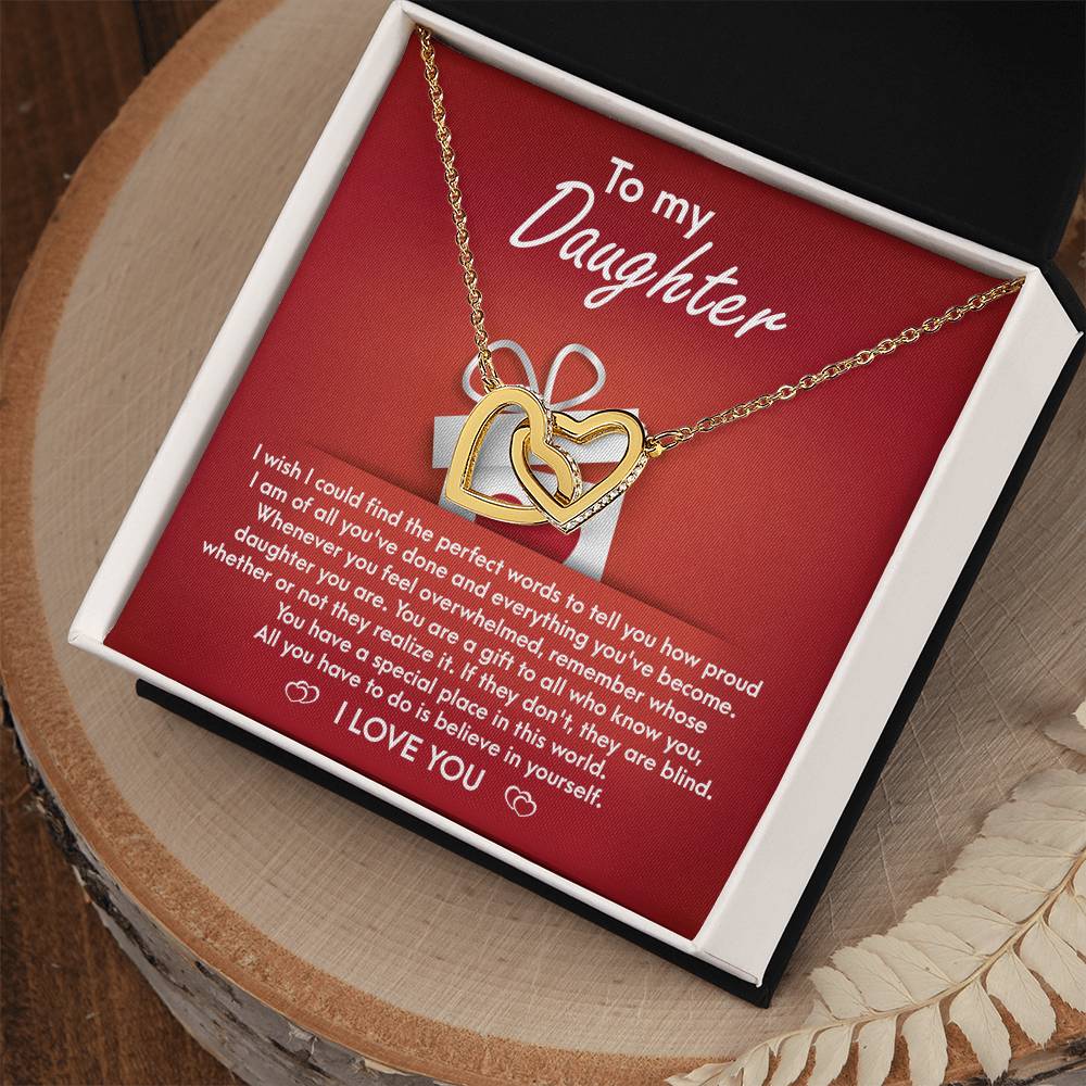 A stunning "To Daughter, A Gift - Interlocking Hearts Necklace" with cubic zirconia crystals is displayed on a red card, featuring a heartfelt message for a daughter, expressing pride, love, and encouragement.