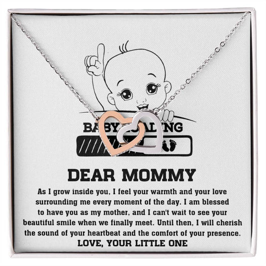A ShineOn Fulfillment necklace, the "To Mama To Be, Your Little One - Interlocking Hearts Necklace" design resplendent with cubic zirconia crystals, displayed over a printed card with a message from an unborn baby to its mother, expressing love and anticipation for their.