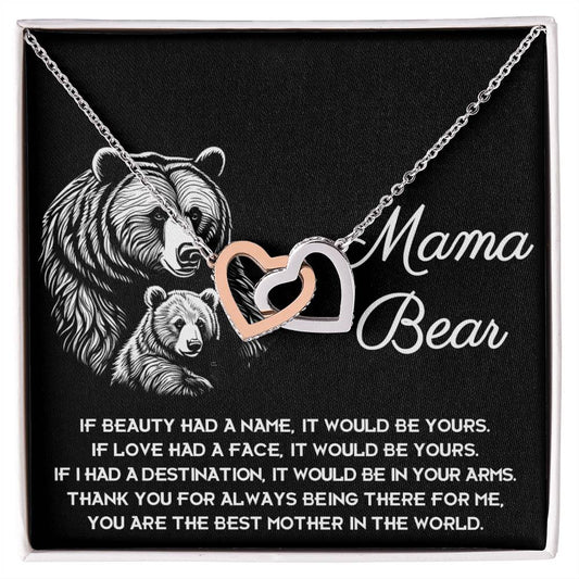 "To Mom, In Your Arms - Interlocking Hearts Necklace" with interlocking heart pendants over a black background, featuring an engraved design of a mother bear and cub, complemented by cubic zirconia crystals and a heartfelt poem titled "M