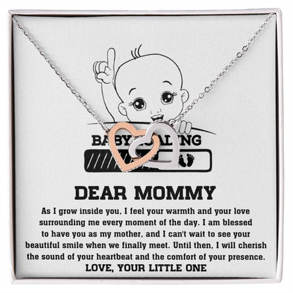 A ShineOn Fulfillment necklace with a pendant featuring an illustration of a baby on a letter to a mother, laying on a cloth surface, adorned with cubic zirconia crystals.