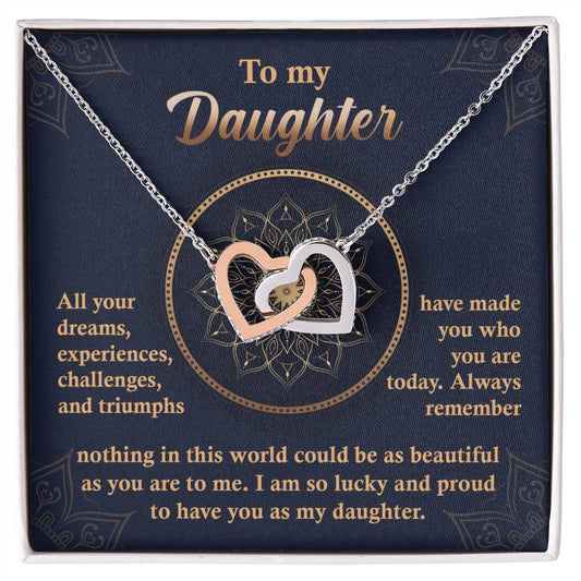 A "To My Daughter, All Your Dreams - Interlocking Hearts Necklace" with a rose gold finish and sparkling cubic zirconia crystals sits in a display box, accompanied by a heartfelt message expressing a parent's pride and love for their daughter.