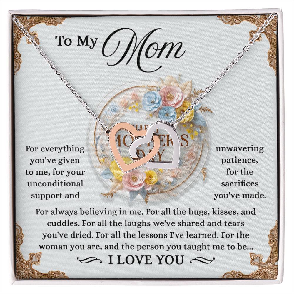 The silver Mom-Taught Me - Interlocking Hearts Necklace, with cubic zirconia crystals, is placed on a floral card addressed "To My Mom." It conveys gratitude for her support, patience, and love, concluding with an "I love you.
