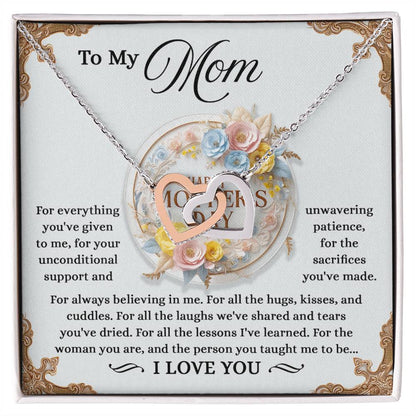 The silver Mom-Taught Me - Interlocking Hearts Necklace, with cubic zirconia crystals, is placed on a floral card addressed "To My Mom." It conveys gratitude for her support, patience, and love, concluding with an "I love you.