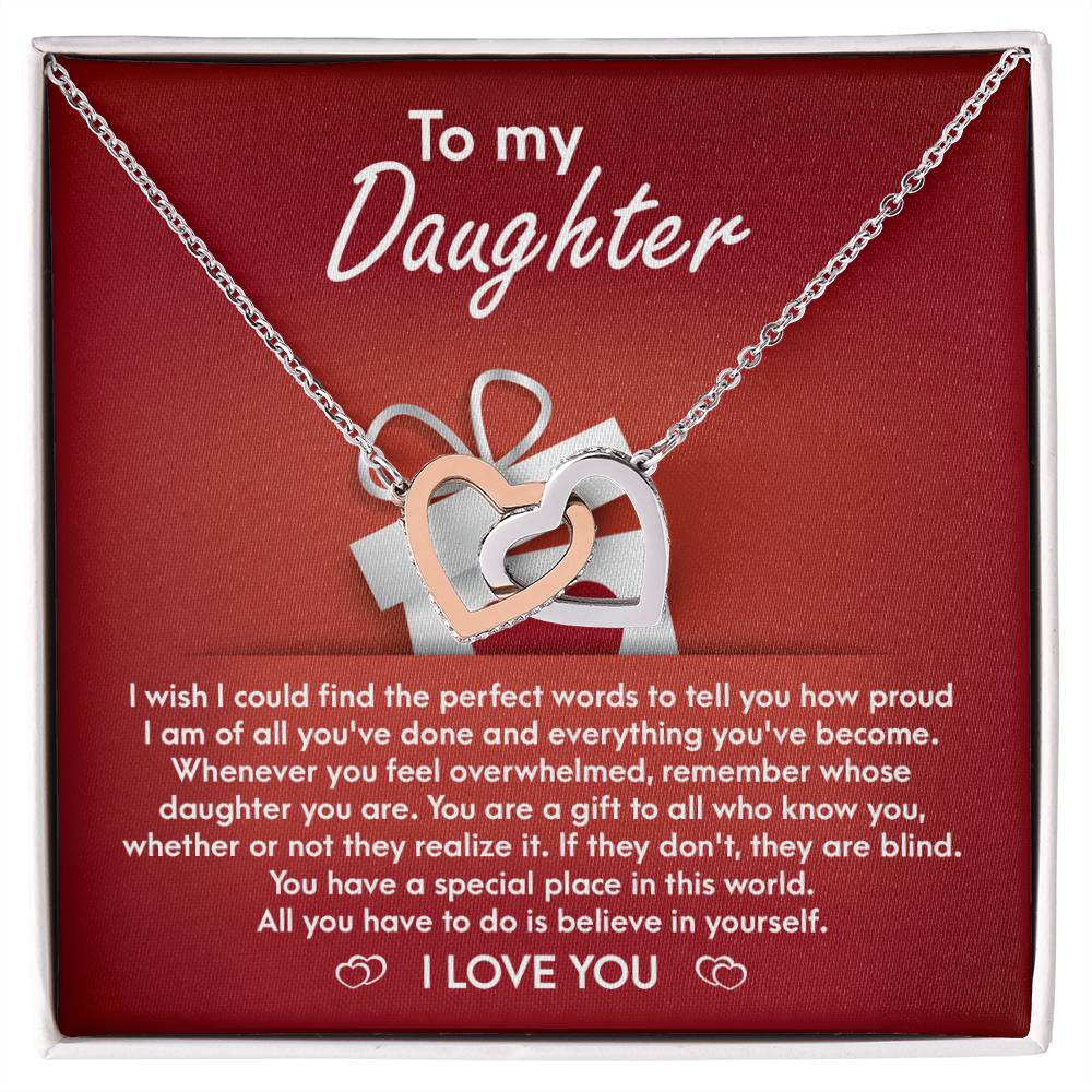 A stunning "To Daughter, A Gift - Interlocking Hearts Necklace" with cubic zirconia crystals is displayed on a red card, featuring a heartfelt message for a daughter, expressing pride, love, and encouragement.