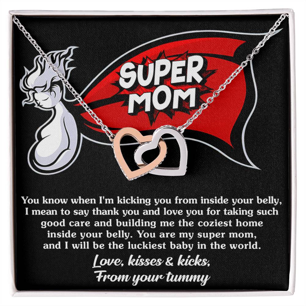 A necklace featuring a "To Mama To Be, My Super Mom" pendant laid on a black surface with a heartfelt thank-you message from an unborn baby to its mother by ShineOn Fulfillment.