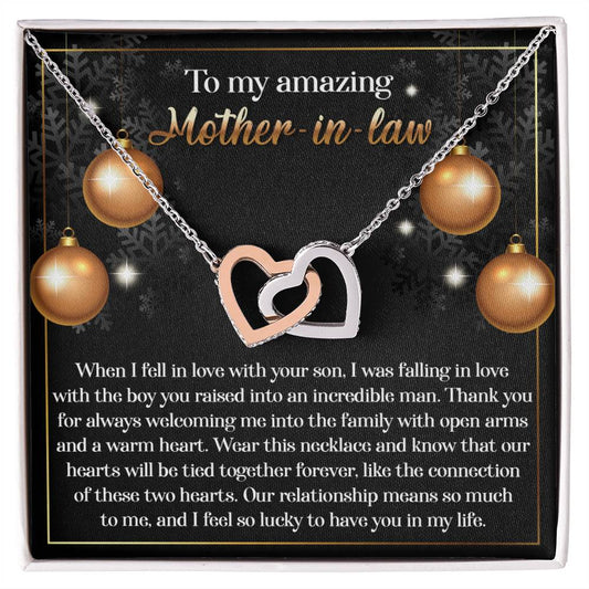 The Mother-in-Law-Two Hearts - Interlocking Hearts Necklace showcases a stunning rose gold finish and is embellished with shimmering cubic zirconia crystals. It comes beautifully presented on a card inscribed with "To my amazing Mother-in-law," complete with a heartfelt message and charming decorative elements, making it an ideal gift to express your love.