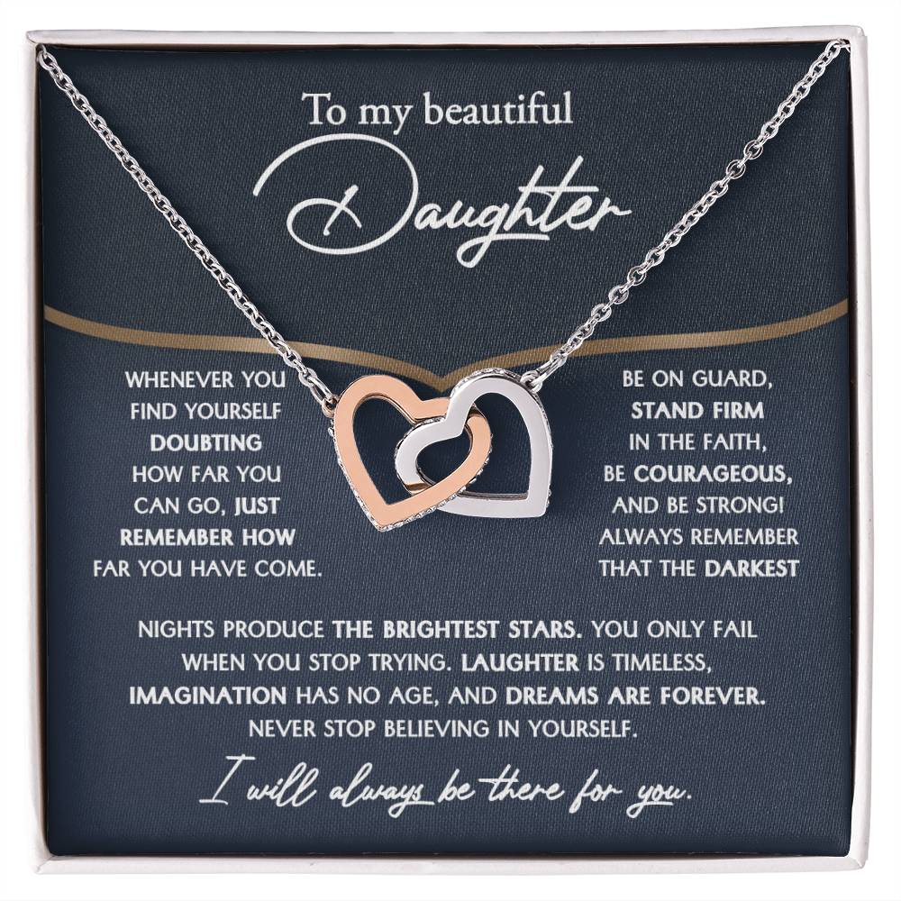 The "To Daughter, Brightest Stars - Interlocking Hearts Necklace," crafted from high-quality polished surgical steel and adorned with cubic zirconia crystals, is presented on a message card addressed to a daughter, offering encouraging and motivational words.