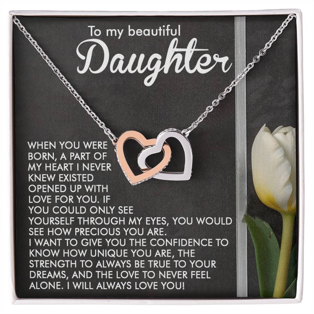 A silver Daughter-Heart Love - Interlocking Hearts Necklace with cubic zirconia crystals is in an open box featuring a loving and confident message for a daughter, alongside an image of a white tulip on the right.