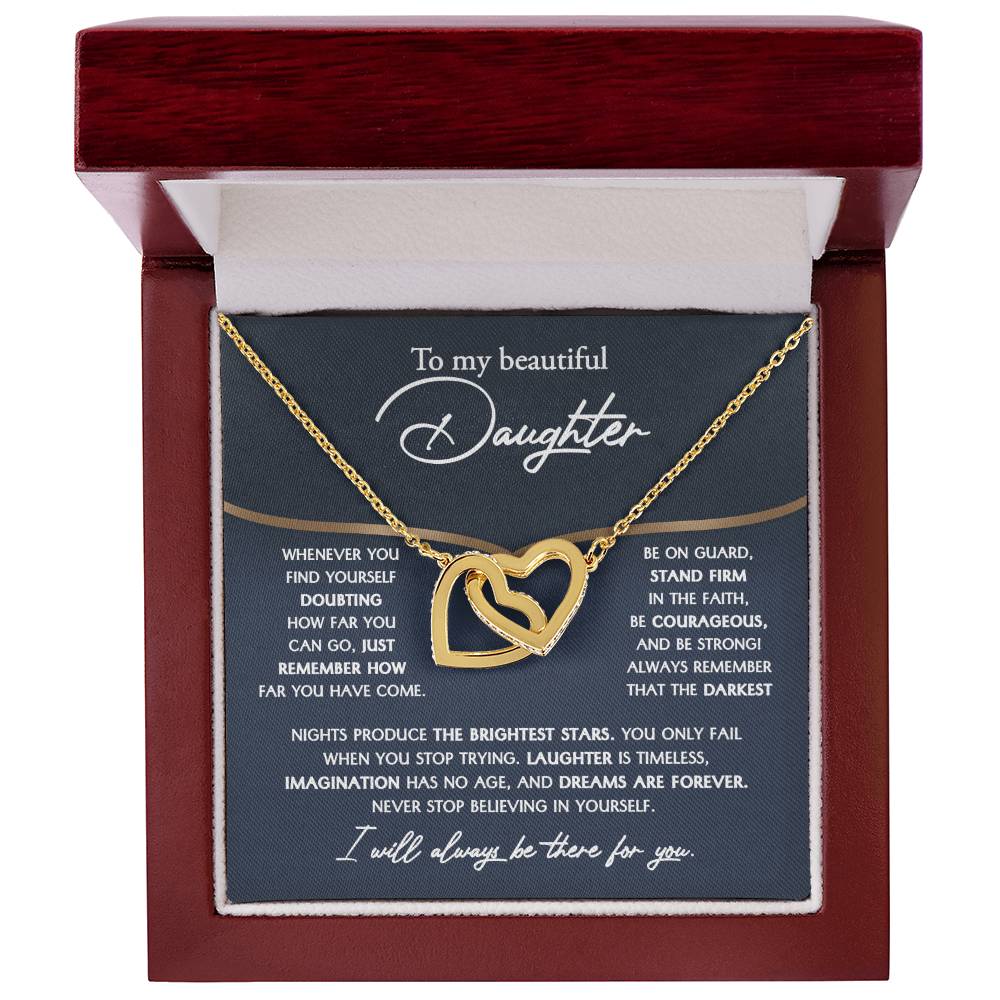 The "To Daughter, Brightest Stars - Interlocking Hearts Necklace," crafted from high-quality polished surgical steel and adorned with cubic zirconia crystals, is presented on a message card addressed to a daughter, offering encouraging and motivational words.